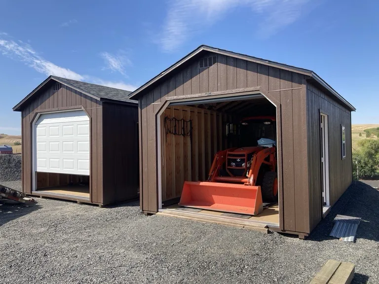 Two brown portable garages with roll-up doors, one housing a tractor