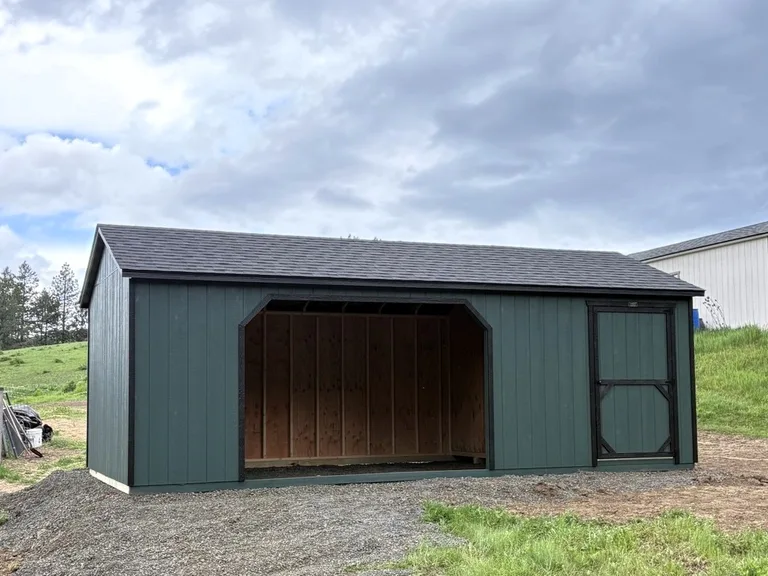 Green horse barn with an open livestock shelter and an enclosed storage room