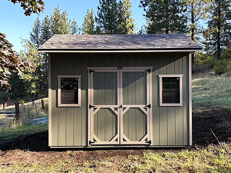 Quaker shed with an overhanging roof, double doors, and two front windows